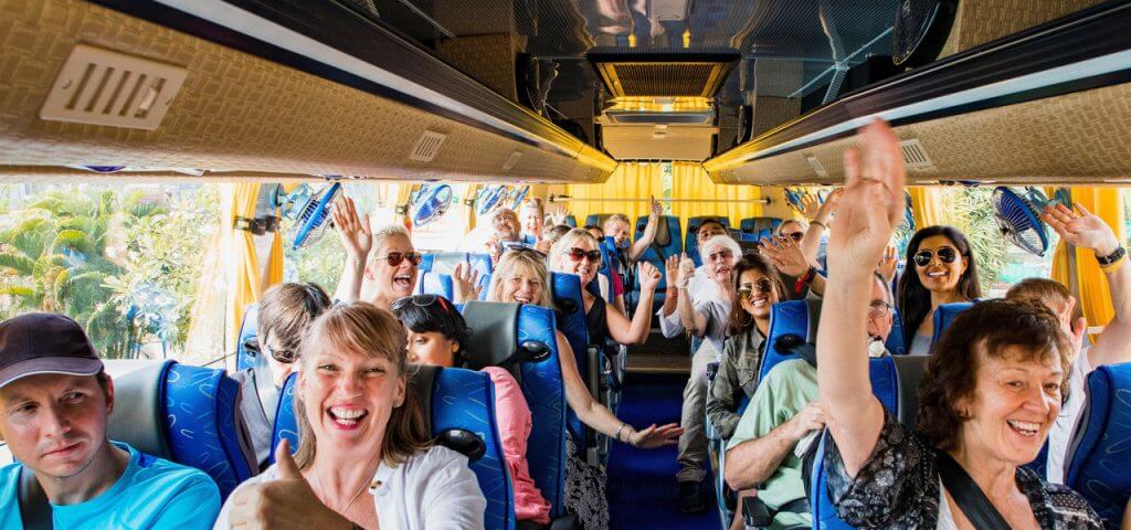 Happy tourists waving from a bus.