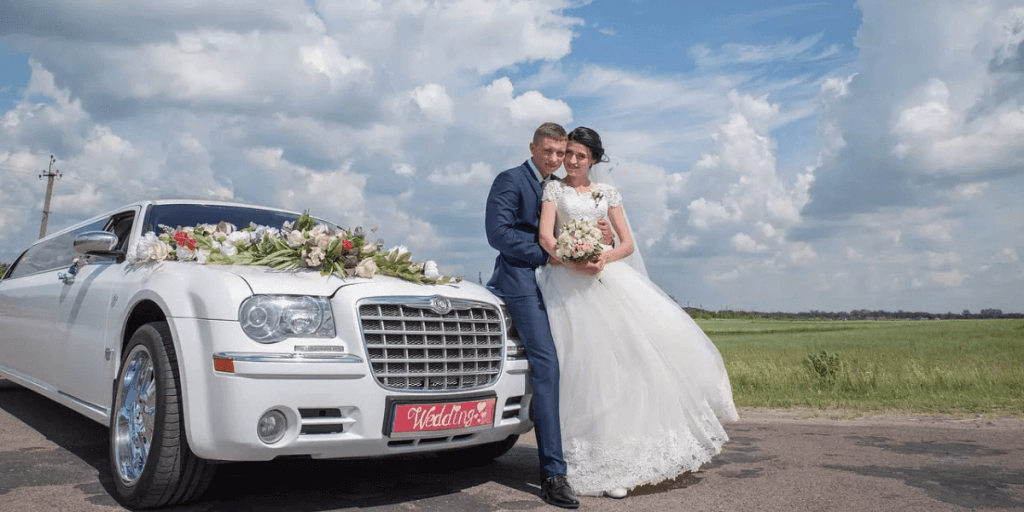 Wedding couple posing with white limousine