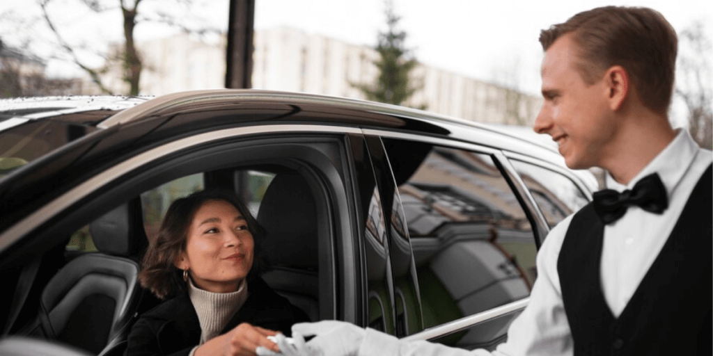 Chauffeur helping passenger exit car.