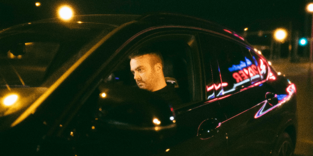 Man in car, neon lights.