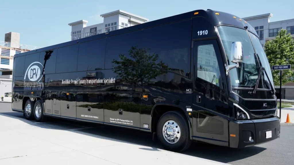 Black luxury charter bus with DPV Transportation logo parked outdoors on a sunny day, chrome wheels gleaming in the light.