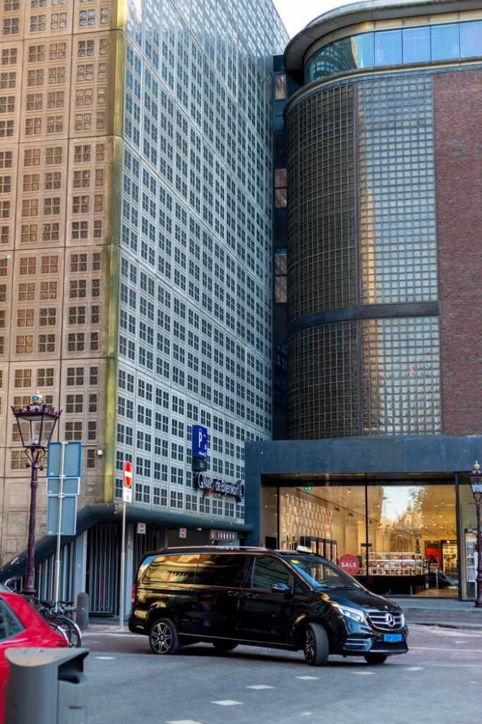 A sleek black Mercedes van parked in front of contemporary urban architecture.