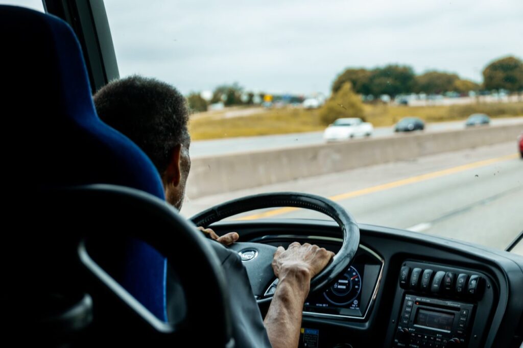 A bus driver skillfully navigating a busy highway with cars in the background.